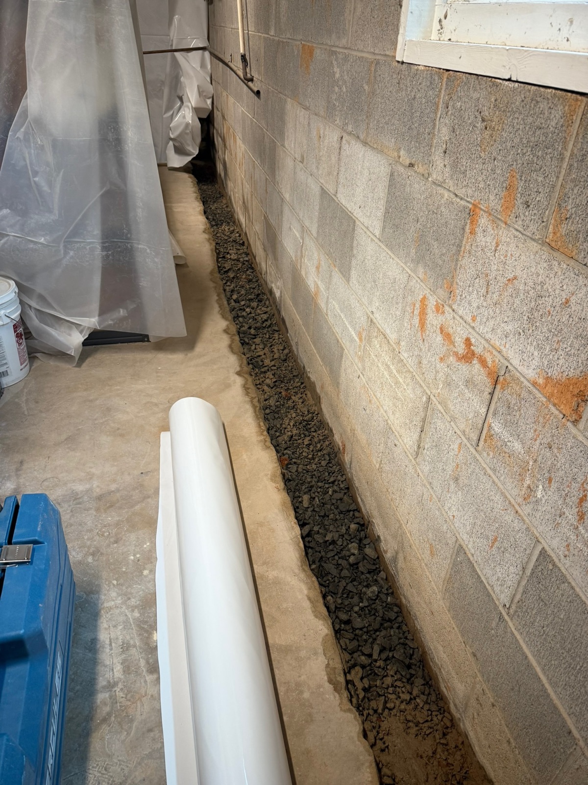 Interior drainage and sump pump being installed at the footing during basement waterproofing