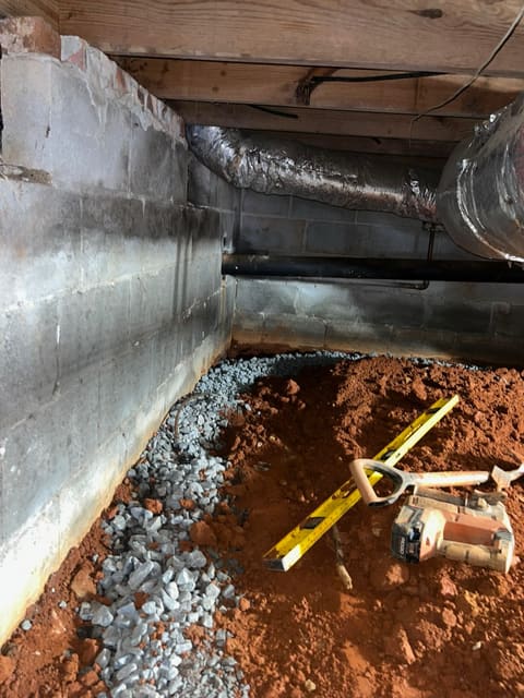 Gravel drainage installed along a crawl space foundation footing dug into Atlanta's red clay soil